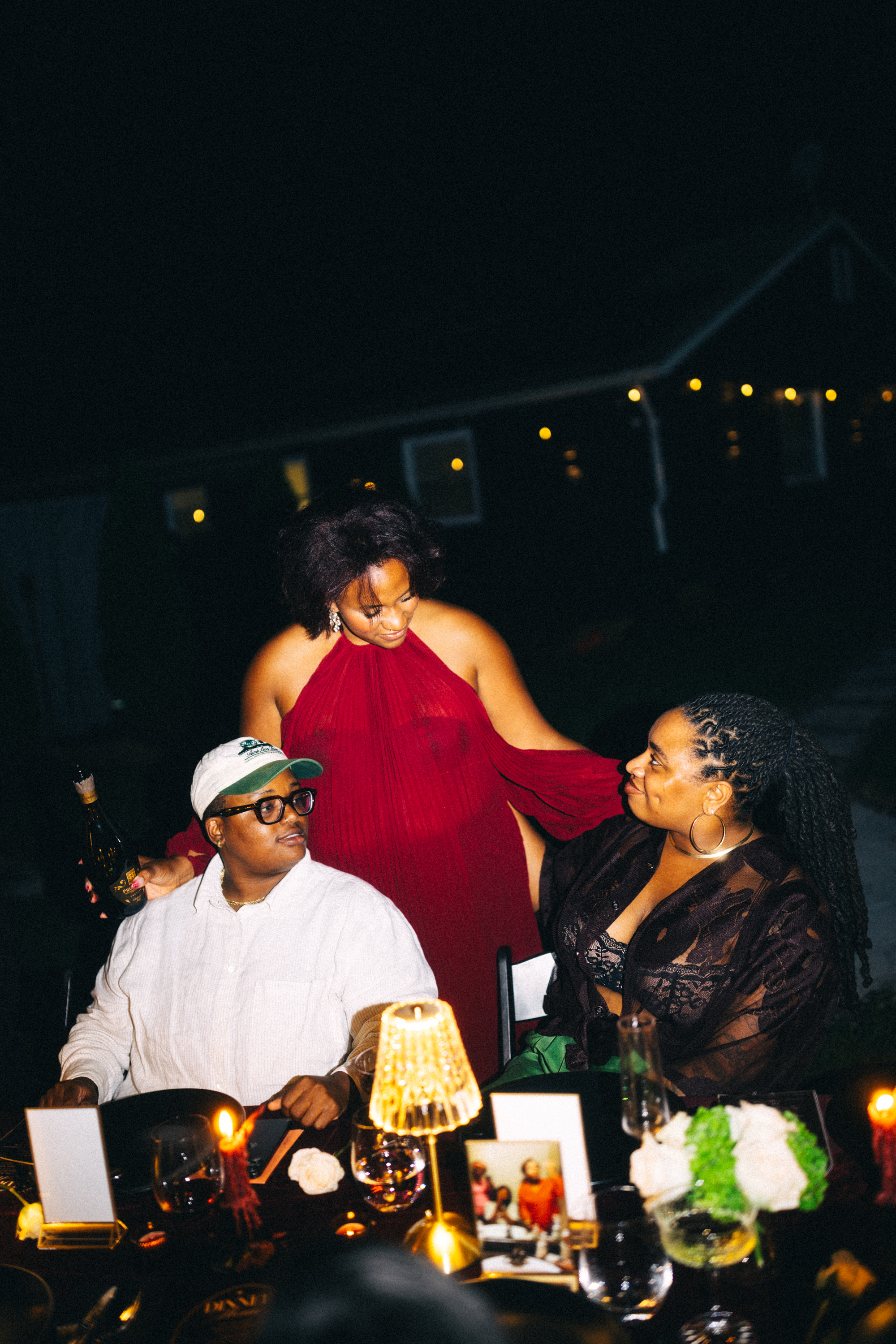 A guest in a red dress leaning in to speak with two seated guests
