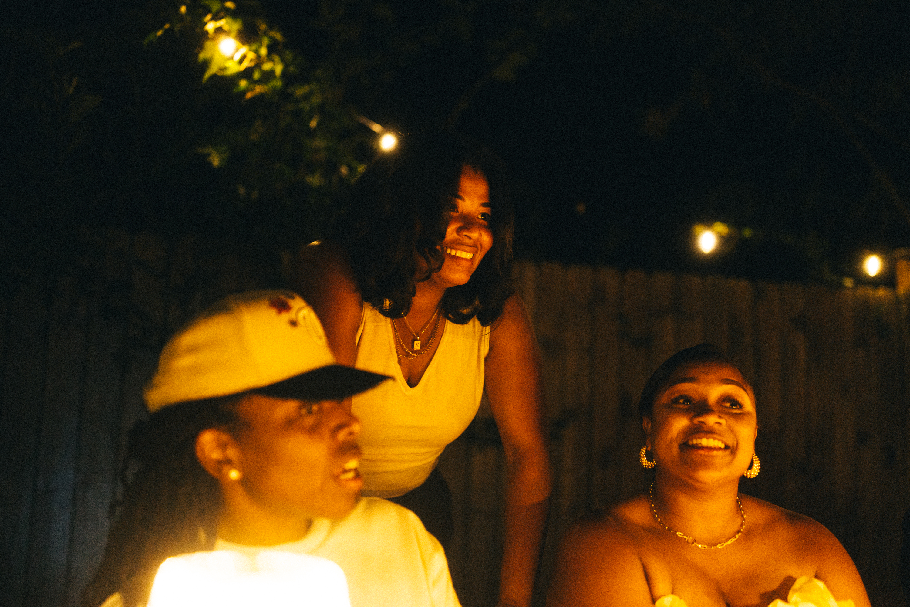 Friends laughing together at a candlelit outdoor table