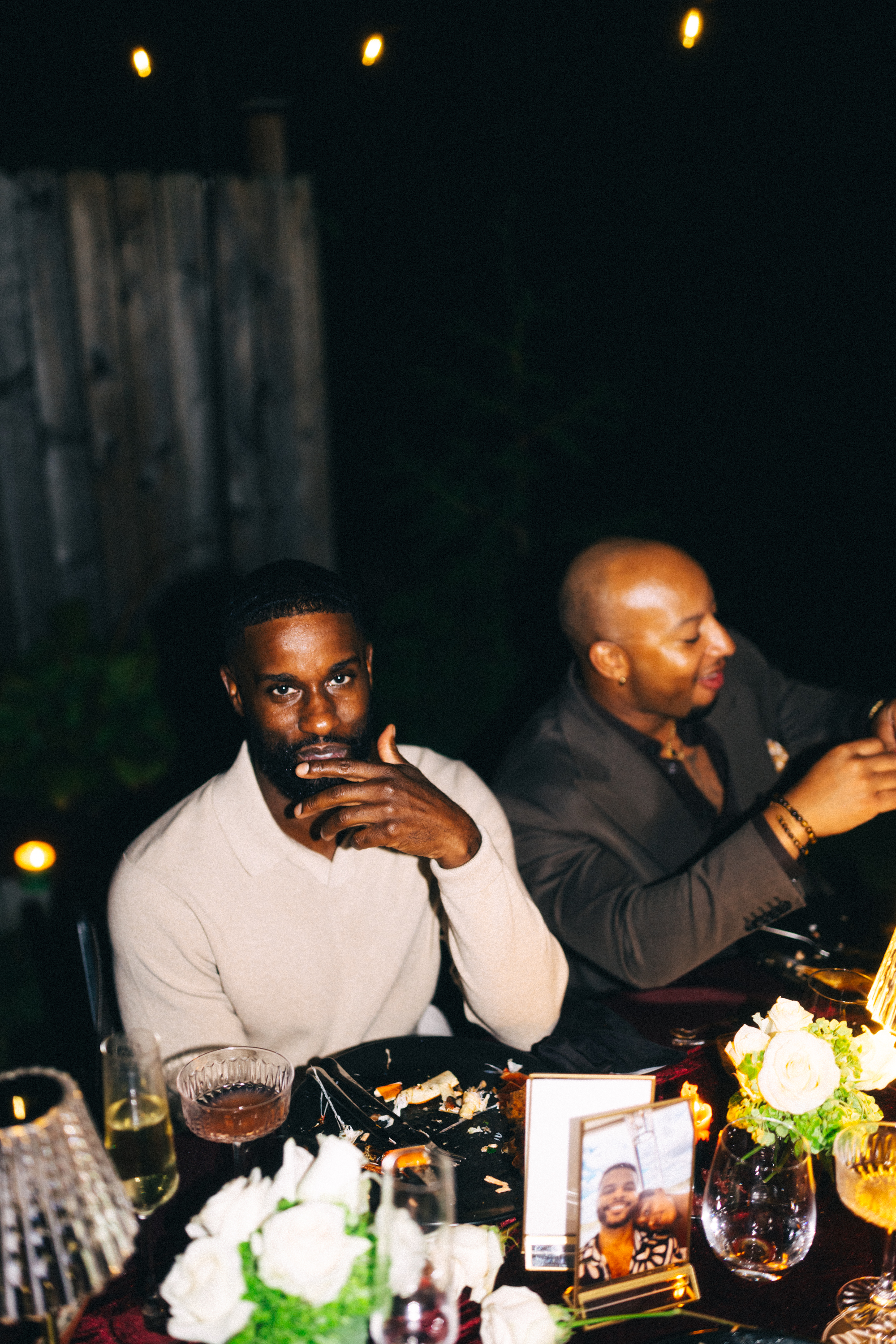 Two guests seated at the candlelit table, one looking toward the camera